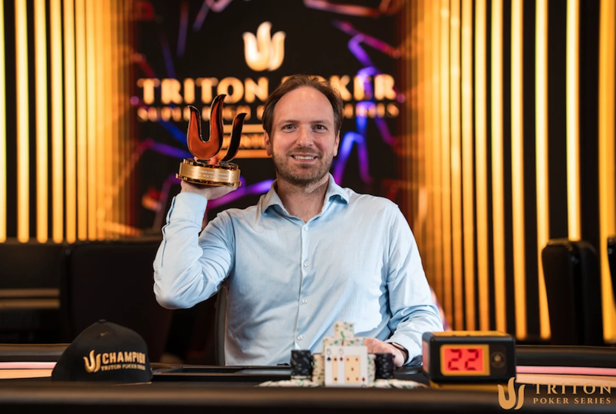 Mike Watson przy stoliku pokerowym podczas Triton Poker Series z trofeum