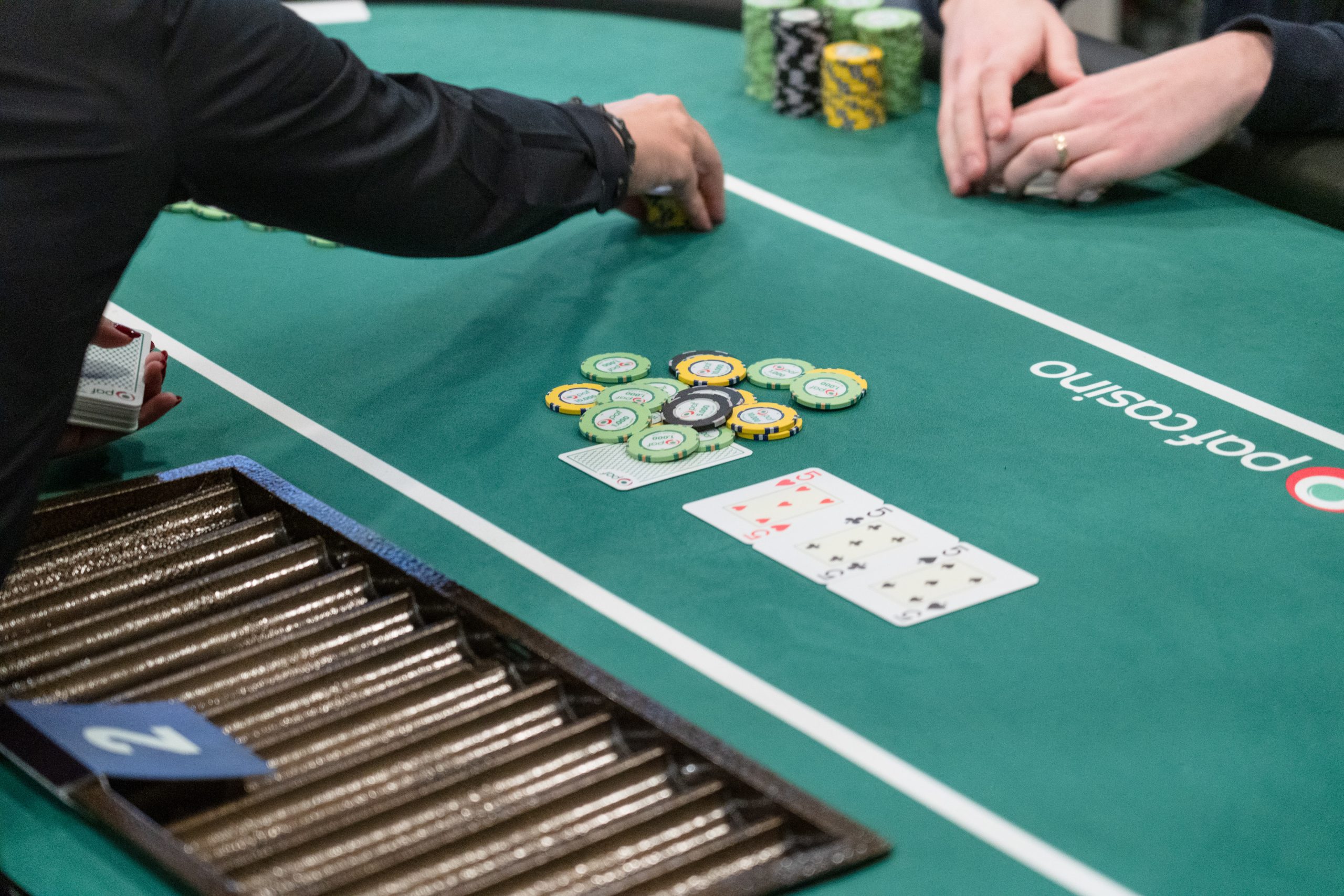 Logo GGPoker na tle stołu pokerowego z żetonami i kartami