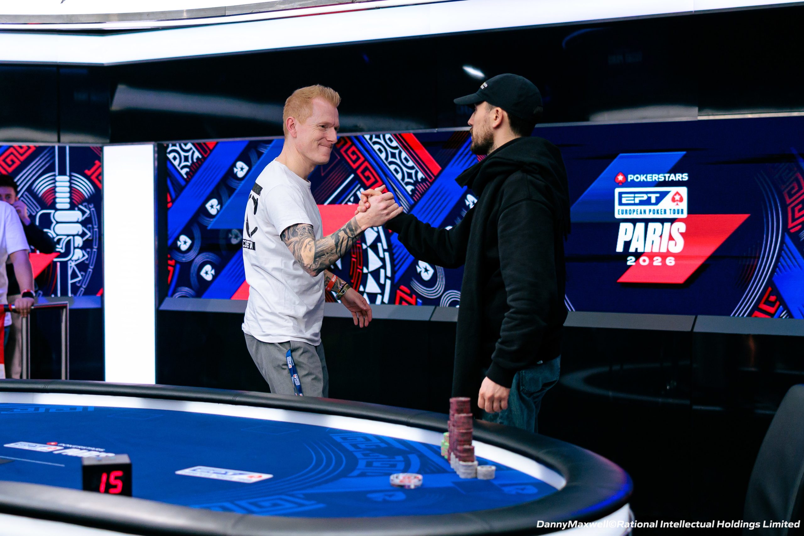 Zdjęcie stołu pokerowego podczas finału turnieju European Poker Tour w Paryżu, z żetonami i kartami.