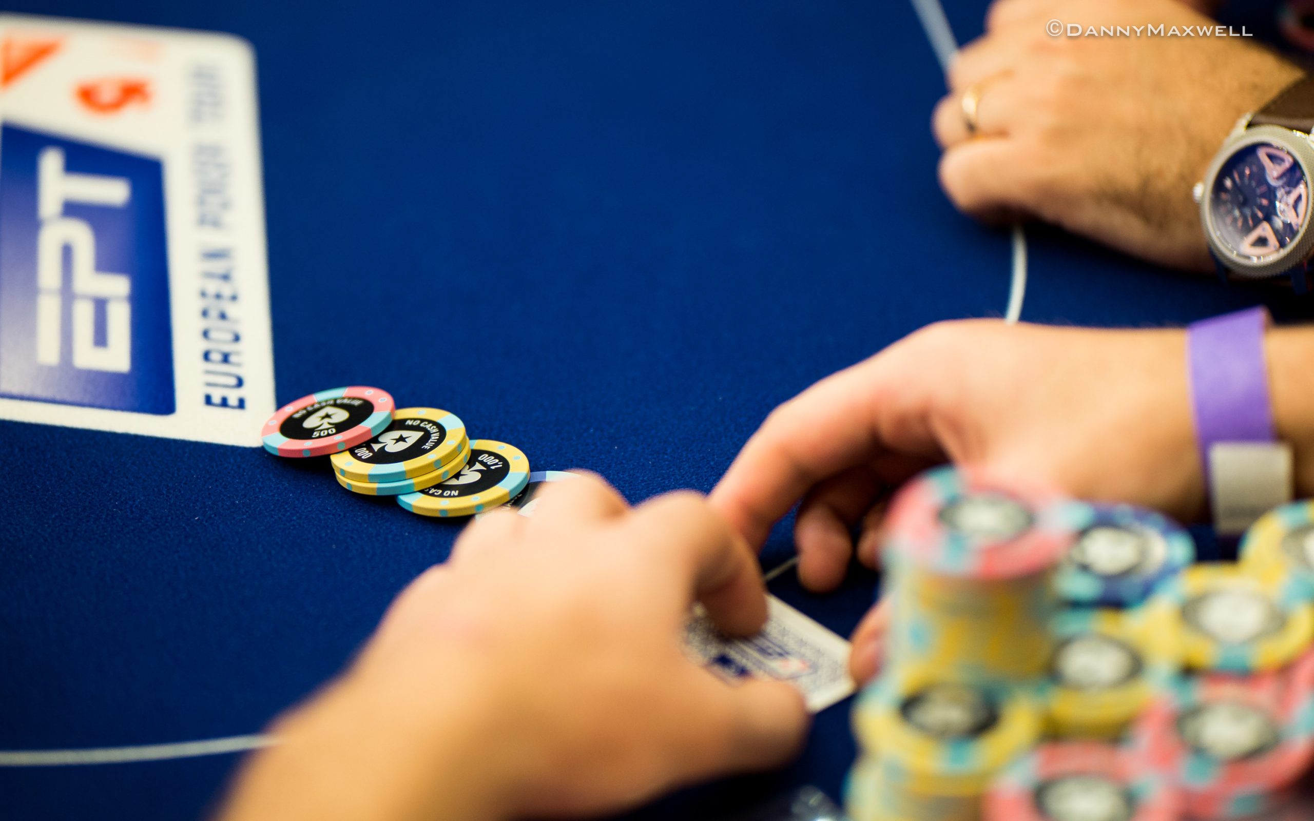 Gracze podczas turnieju pokerowego analizujący swoje karty i żetony przy stole.