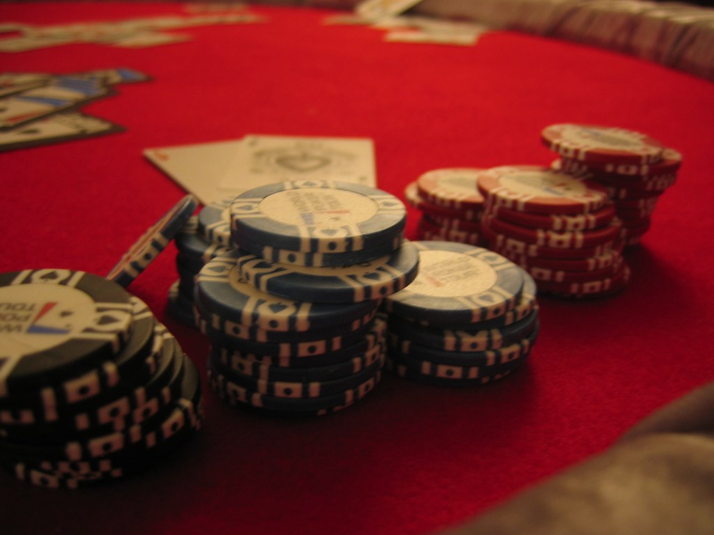 Logo GGPoker na tle stołu do pokera online z wirtualnymi żetonami i kartami