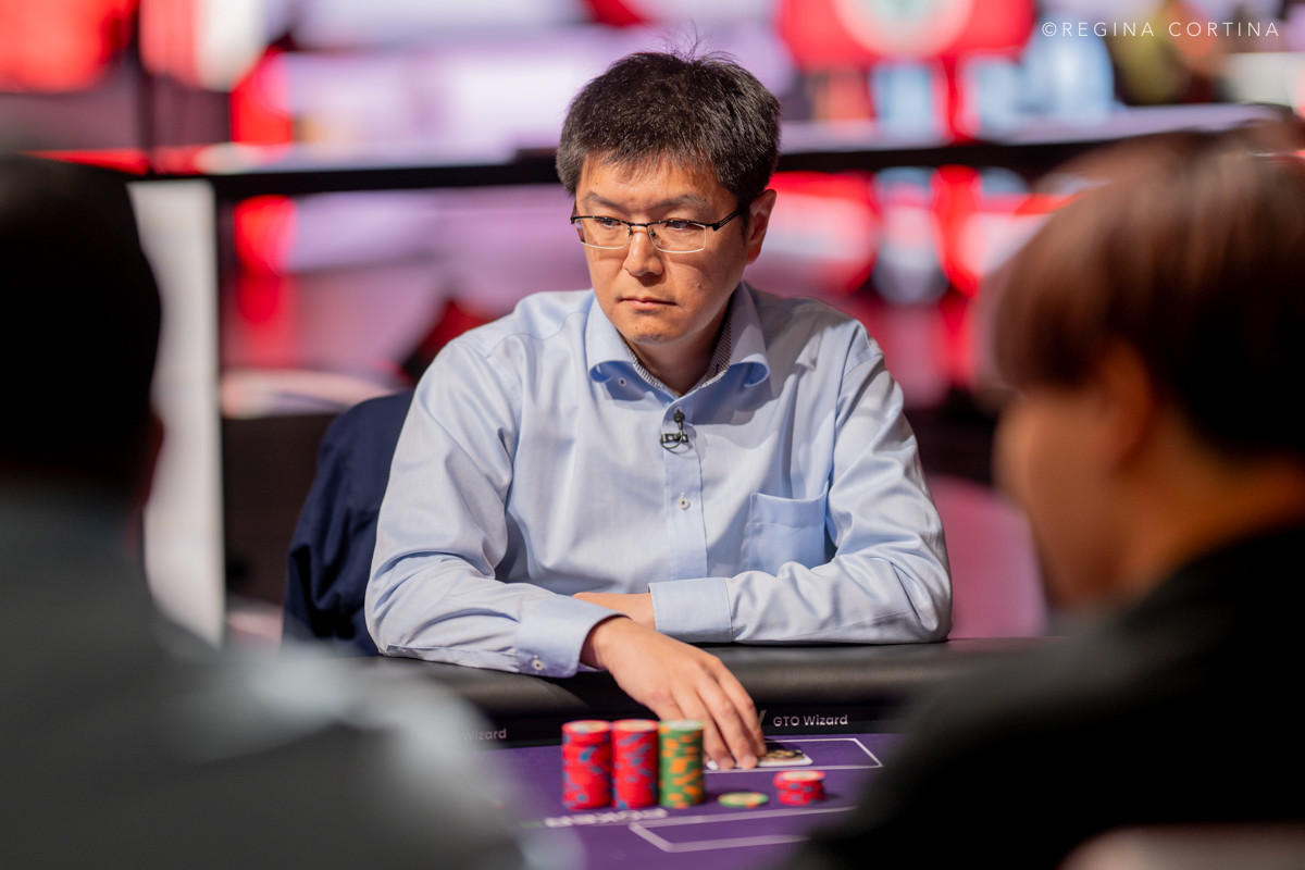 Gracze przy stole pokerowym podczas turnieju World Series of Poker, z żetonami i kartami na stole.