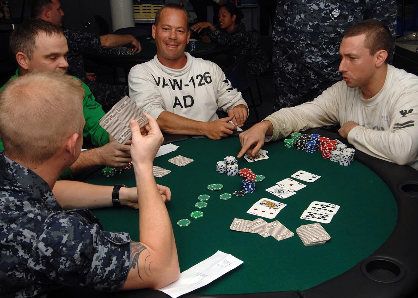 Wirtualny stół pokerowy GGPoker widoczny na ekranie laptopa, z kartami i żetonami.