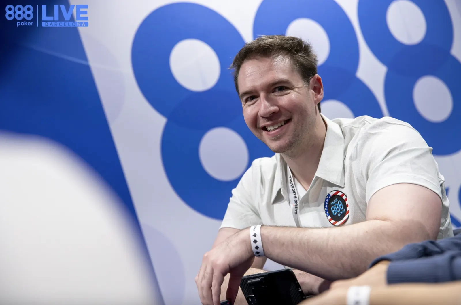 Finałowy stół turnieju pokerowego z graczami przy stole i stosami żetonów.