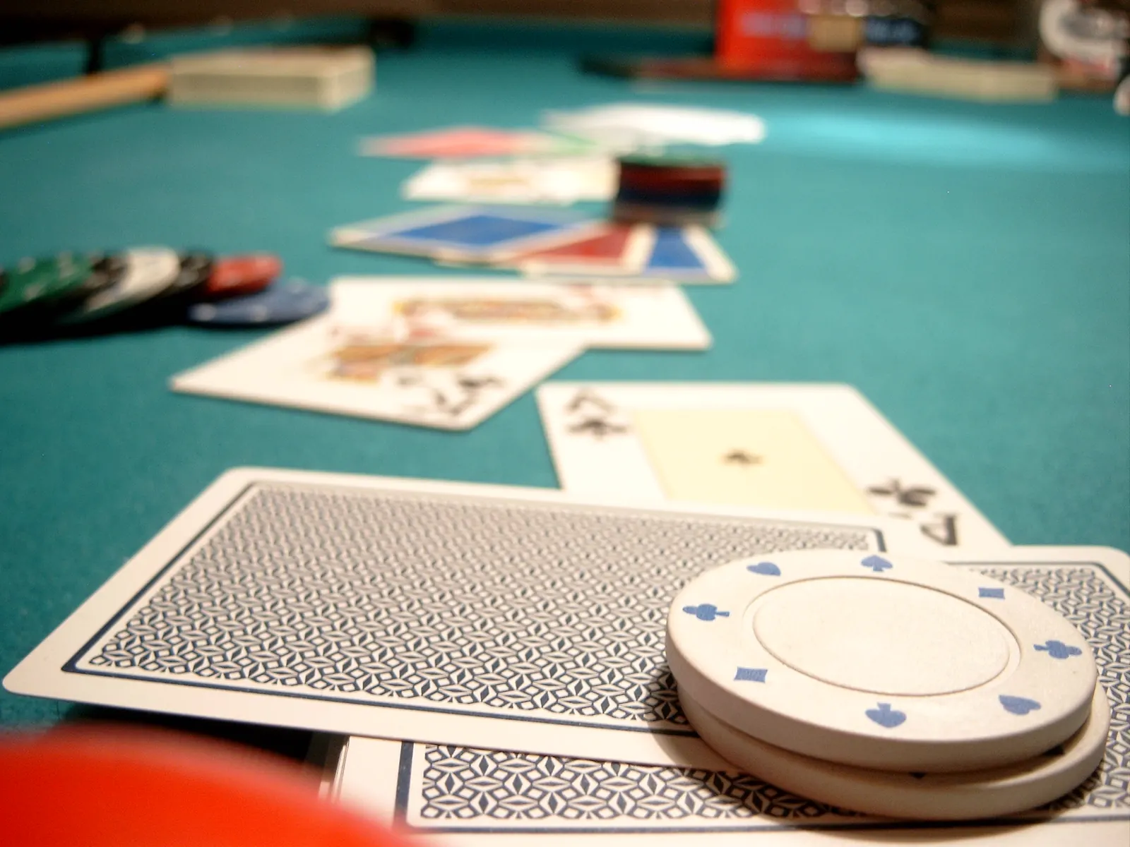 Stół pokerowy z kartami i żetonami, logo GGPoker na tle turnieju online